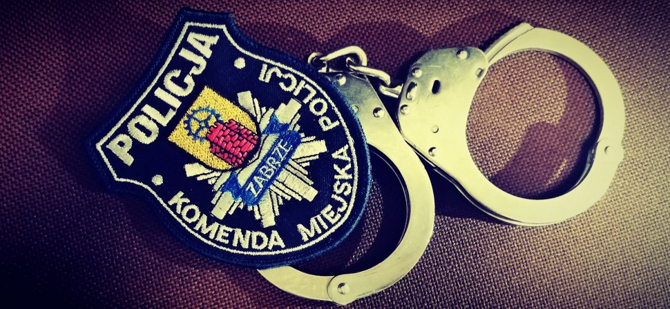 Zdjęcie kolorowe: emblemat Komendy Miejskiej Policji w Zabrzu i kajdanki