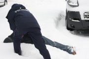 Policjant przy osobie, która leży w śniegu