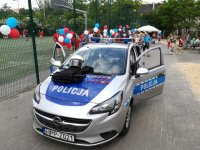 zdjęcie kolorowe: policyjny radiowóz i dzieci z przedszkola