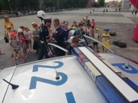 Zdjęcie kolorowe: dzieci zbierają się obok policyjnego radiowozu