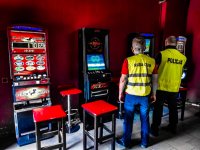 Zdjęcie kolorowe: policjant i funkcjonariusz KAS stoją w lokalu którym zabezpieczono nielegalne automaty